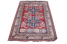 A flat weave red, blue and cream rug. With zoomorphic patterns on a rust-red ground, 187cm x 133cm.