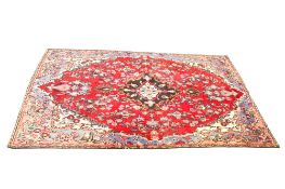 A Persian style wool rug on a red and blue ground.