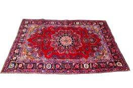 A Persian style wool rug on a red ground. With multiple geometric border on a blue ground.