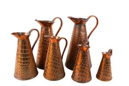 A set of six Joseph Sankey & Son Arts and Crafts graduated copper jugs.