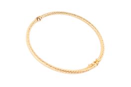 An 18ct gold hinged bangle. Having a textured band and secured by a clip lock, gross weight 7.