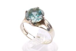 A white metal dress ring. Set with one round faceted blue zircon of circa 9.5mm diameter.