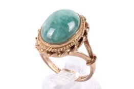 A 9ct gold and jade ring. The mottled cabochon 1.3cm x 1cm, hallmarked, size K, gross weight 5.2g.