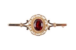 A 9ct gold and garnet bar brooch. The faceted oval stone circa 9mm x 7mm, hallmarked, L4.