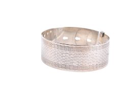 A contemporary silver belt cuff bangle. Having engraved decoration and four size settings, 28.