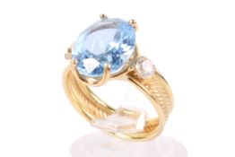 A yellow metal and topaz dress ring. The oval cut pale blue stone circa 1.