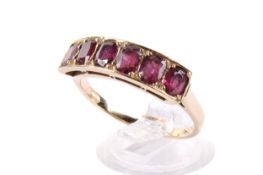 A yellow metal ring set with oval faceted garnets. Unmarked, but tested as 9ct gold.