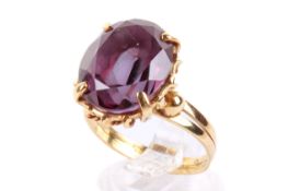 A yellow metal and amethyst dress ring. The faceted oval stone circa 1.