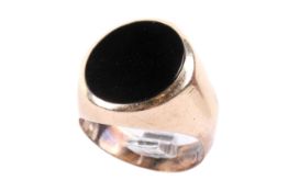 A yellow metal and black stone ring. The black oval circa 1.4cm x 1.