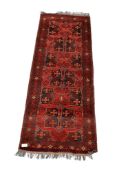 A small Persian style wool runner on a red ground.