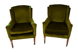 A near pair of green upholstered wingback arm chairs. Having square tapering supports with casters.