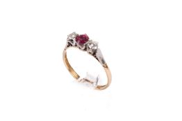 An 18ct gold and platinum (stamped) three stone ring. Set with one round faceted pink sapphire of 0.