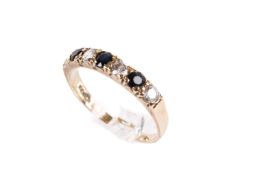 A hallmarked 9ct gold ring set with dark blue sapphires and synthetic spinel.