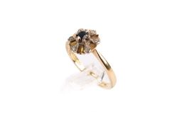 An 18ct gold stone ring. Set with one round faceted sapphire and a border of single cut diamonds.