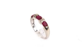 A 9ct gold and ruby dress ring. Set with three rubies (very worn) and single cut diamonds.
