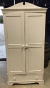 A modern painted pine wardrobe, the shaped top above two panelled doors,