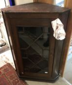 An early 19th Century oak corner cabinet with glazed door opening to reveal three painted shelves