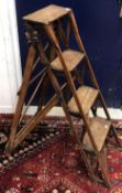 A vintage pair of wooden four tier steps, bearing iron label 