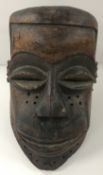 An African Chokwe carved treenware, fabric and cowrie shell embellished mask of large proportions,