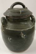 A Winchcombe Pottery glazed jar and cover with eye type decoration on a mottled green ground