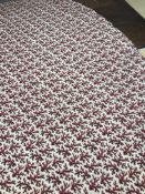 A padded circular table cover in a cream and red coral design,