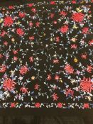 A piano shawl in black silk with foliate design predominantly in reds and blues,