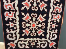 A wool wall hanging in red and grey on a blue background,