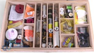 An assortment of fly tying materials including silks, feathers, wool, packets of dyed materials, a