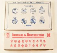 Two framed boxed badge sets to include a Real Madrid Football Club silver badge set and a 2003/