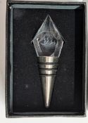 A crystal topped wine stopper with a sail boat image.