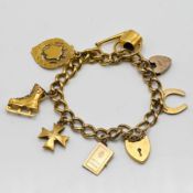 A charm bracelet set with an arrangement of gold, silver gilt and yellow metal charms to include 9ct
