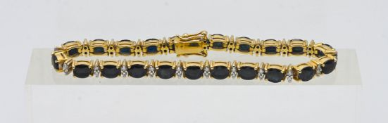 A 14k yellow gold sapphire and diamond set line bracelet, set with oval deep blue sapphire's with