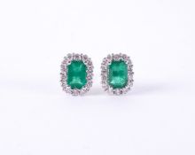 A pair of 18ct white & yellow gold cluster style earrings set with a central emerald cut emerald,