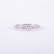 A platinum ring set with a central round brilliant cut diamond, approx. 0.15 carats, with six