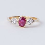 An 18ct yellow gold three stone ring set with a central oval cut ruby, approx. 0.35 carats with a