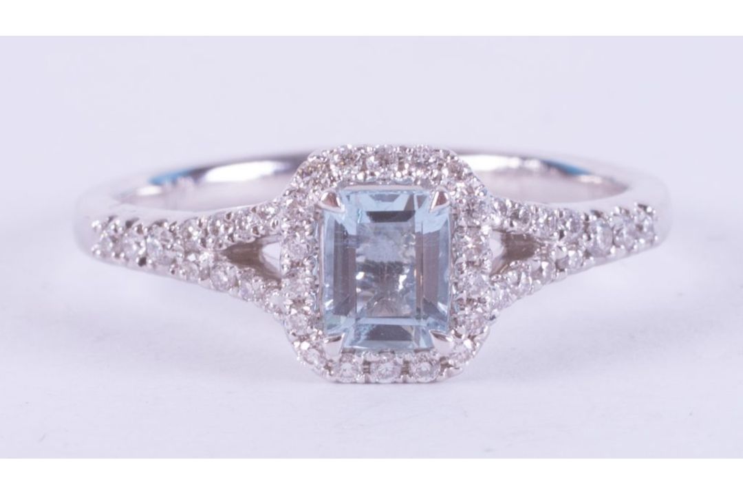 An 18ct white gold ring set with a central emerald cut aquamarine, approx. 0.50 carats, surrounded - Image 1 of 2