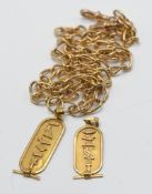 A pair of high carat gold Egyptian pendants, one on a 9ct gold albert chain and another loose, total