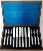 A Chinese silver six setting dessert set (knives and forks), decorated with prunus in relief, in