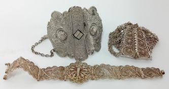 Three ornate Indian silver jewellery pieces comprising a cuff bangle and two bracelets. (3).