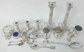 A quantity of silver, to include a pair of column candlesticks (one broken), spoons, mugs, cruet