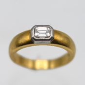 A modern 18ct yellow gold ring set with an emerald cut diamond,