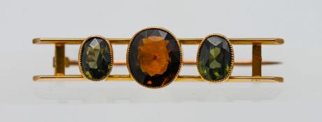 A gem set bar brooch, set with three stones in 15ct yellow gold, approx 5.10g.