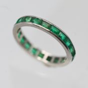 A platinum and emerald full eternity ring, of channel set design, size O/P (not hallmarked).