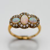 A three stone opal ring set with diamonds all the way round, set in yellow gold (not hallmarked),