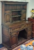 A Georgian oak dresser in two parts. The upper section with shelves and cupboards, the base fitted