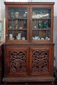 A 19th century carved mahogany display cabinet, the upper section with two glazed doors with brass