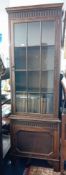 A 1920's oak narrow bookcase with single door, fitted with 12 glazed panels and a lower cupboard