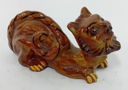 A grotesque pottery cat by Hart & Moist Exeter, brown glaze with black and yellow details, length