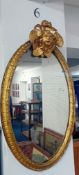 A 19th century oval wall mirror with gilt frame and ornate cherub pediment. Height 75cm, width