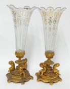 A pair of gilt candle lamps, the fluted glass with gilt painted floral motifs, seated figures to